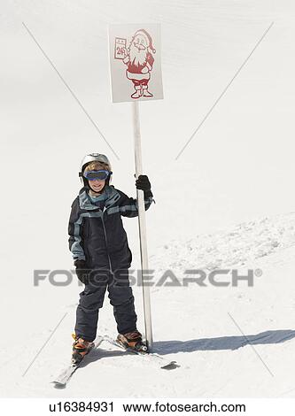 Stock Image - Boy skier holding Santa sign. Fotosearch