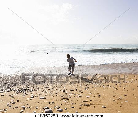 Boy skimming stone on beach View Large Photo Image Stock Image - Boy skimming stone on beach. Fotosearch