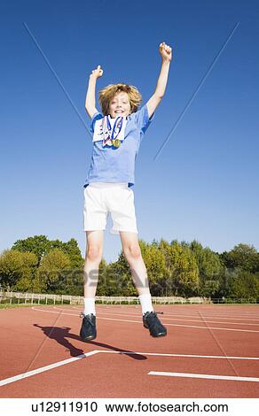 Stock Image - Boy with medals Jumping on Race Track. Fotosearch