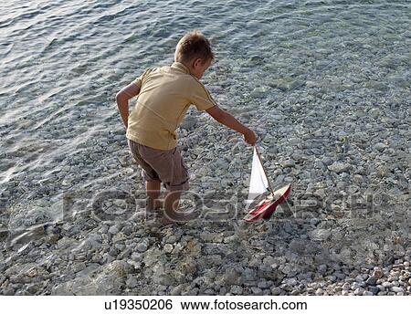 Boy with toy boat at beach View Large Photo Image Stock Photograph - Boy with toy boat at beach. Fotosearch