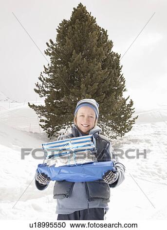 Stock Image - Boy with Xmas presents in snow. Fotosearch