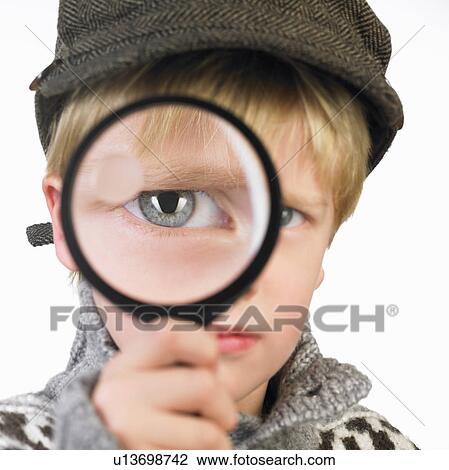 Stock Image - Boy's eye through a magnifying glass. Fotosearch