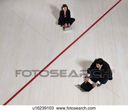 Stock Image - Business man and woman on laptops. Fotosearch