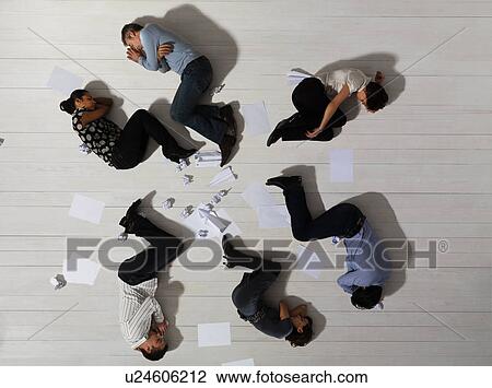 Stock Image - Business men and women asleep on floor. Fotosearch