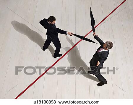 Stock Photo - Business men fighting with umbrellas. Fotosearch