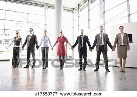 Business people holding hands in office View Large Photo Image Stock Photo - Business people holding hands in office. Fotosearch
