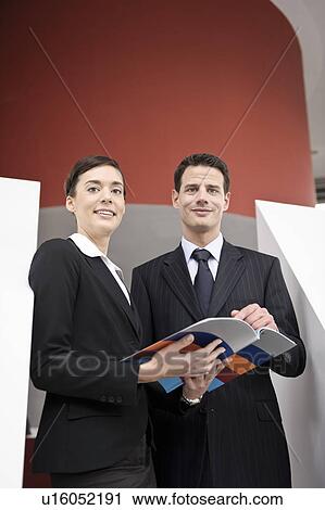 Stock Image - Business people looking at brochure. Fotosearch