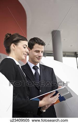 Stock Photography - Business people looking at brochure. Fotosearch