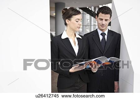 Stock Photography - Business people looking at brochure. Fotosearch