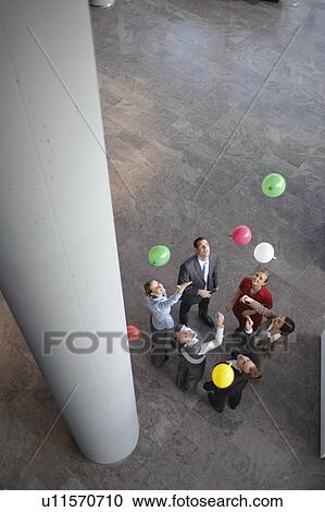 Stock Image - Business team sets colored balloons free. Fotosearch