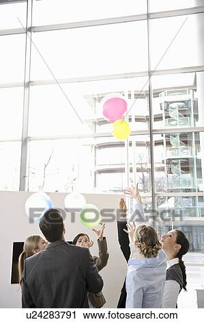 Stock Image - Business team sets colored balloons free. Fotosearch
