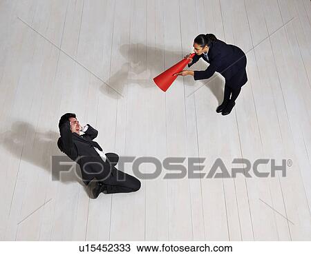 Stock Image - Business woman shouting at man on floor. Fotosearch