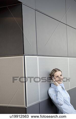 Stock Image - Business woman using mobile in office. Fotosearch