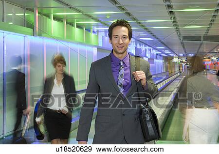 Stock Photo - businessman at airport, walking, happy. Fotosearch