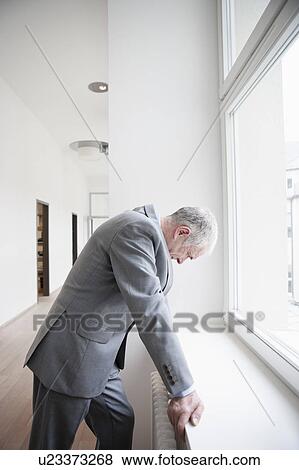 Stock Photo - Businessman leaning against window. Fotosearch