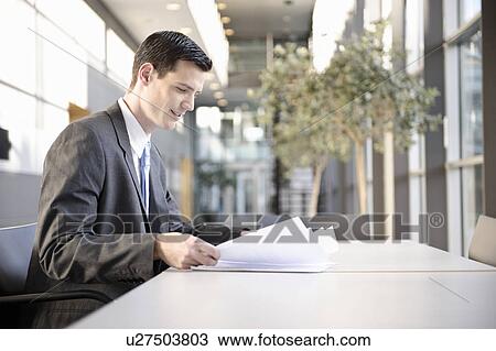 Stock Image - Businessman looking at blueprint. Fotosearch