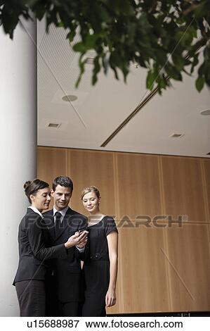 Stock Photo - Businessman show coworkers his cellphone. Fotosearch