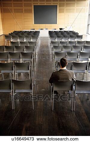 Businessman sitting at back of empty con View Large Photo Image Stock Image - Businessman sitting at back of empty con. Fotosearch