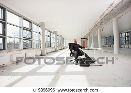 Businessman sitting in future office View Large Photo Image Stock Photograph - Businessman sitting in future office. Fotosearch