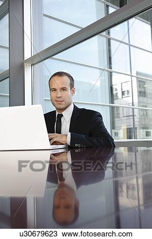 Businessman working with laptop, smiling View Large Photo Image Stock Image - Businessman working with laptop, smiling. Fotosearch