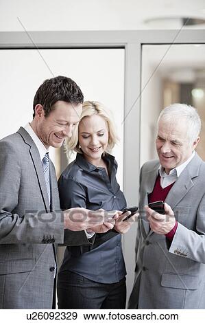 Businesspeople checking handhelds View Large Photo Image Stock Photo - Businesspeople checking handhelds. Fotosearch