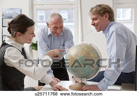 Businesspeople looking at globe View Large Photo Image Stock Photo - Businesspeople looking at globe. Fotosearch