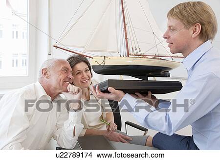 Picture - Businesspeople looking at model ship. Fotosearch