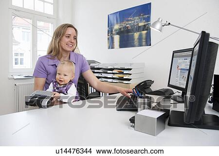 Picture - Businesswoman and baby in office. Fotosearch