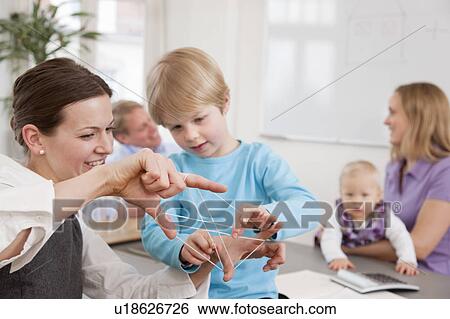 Businesswoman, boy playing string game View Large Photo Image Stock Photograph - Businesswoman, boy playing string game. Fotosearch