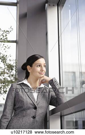 Businesswoman looking out office window View Large Photo Image Stock Photo - Businesswoman looking out office window. Fotosearch
