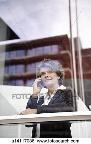 Stock Photograph - Businesswoman using cell phone, smiling. Fotosearch