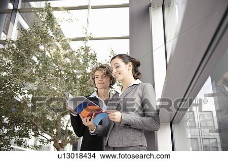 Businesswomen looking at brochure View Large Photo Image Picture - Businesswomen looking at brochure. Fotosearch