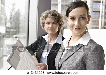 Stock Photo - Businesswomen looking at brochure. Fotosearch