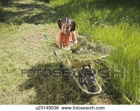 Stock Photograph - Child sitting on hay in wheelbarrow. Fotosearch
