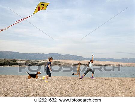 Stock Image - Children flying kite at beach. Fotosearch