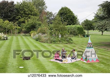 Stock Image - Children having picnic beside teepee. Fotosearch