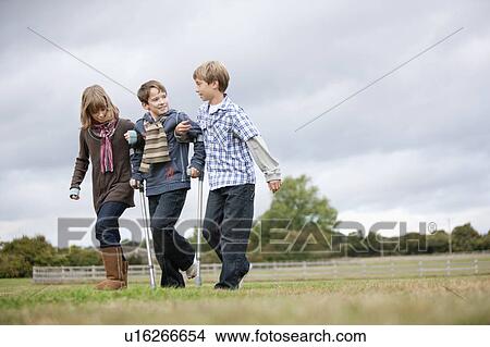 Picture - Children helping boy on crutches. Fotosearch