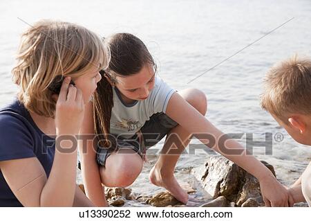 Children listening to shells at beach View Large Photo Image Stock Image - Children listening to shells at beach. Fotosearch