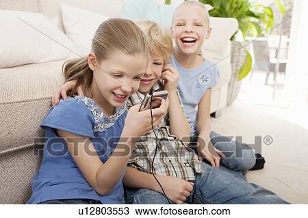 Stock Image - Children playing with an MP3 player. Fotosearch