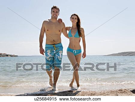 Stock Photography - Couple coming out of water at beach. Fotosearch
