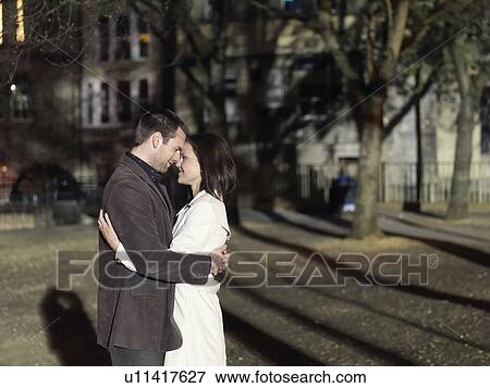 Couple hugging in park at night View Large Photo Image Stock Photo - Couple hugging in park at night. Fotosearch