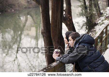 Couple relaxing by river in winter View Large Photo Image Stock Photograph - Couple relaxing by river in winter. Fotosearch