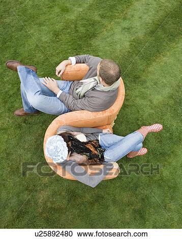 Stock Image - Couple sitting on love-seat outdoors. Fotosearch