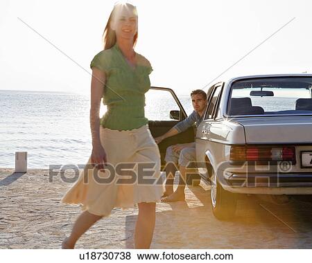 Stock Photo - Couple with oldtimer by sea. Fotosearch