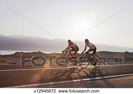 Cyclists on country road by sea View Large Photo Image Stock Image - Cyclists on country road by sea. Fotosearch