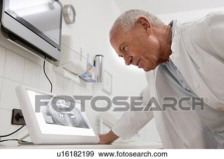 Dentist looking at x-ray View Large Photo Image Stock Photo - Dentist looking at x-ray. Fotosearch