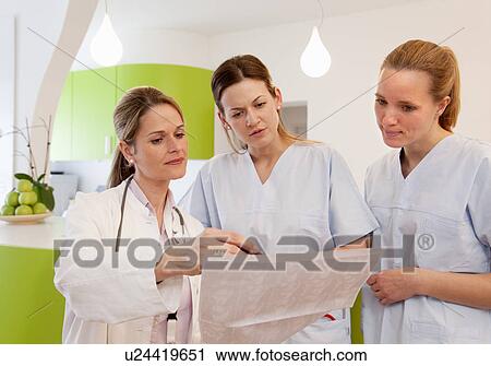 Stock Image - Doctor and nurses studying chart. Fotosearch