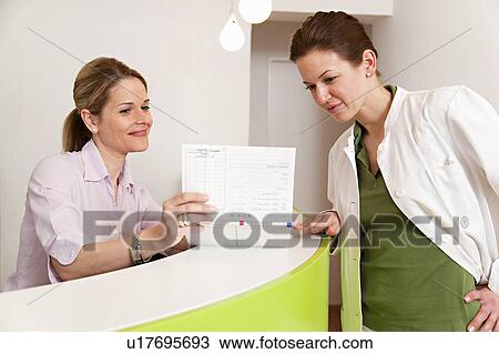 Stock Image - Doctor and receptionist in surgery. Fotosearch