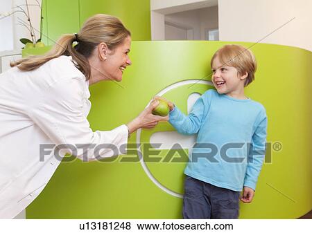 Stock Photo - Doctor giving apple to boy. Fotosearch