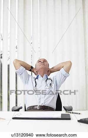 Stock Image - Doctor leaning back on a chair. Fotosearch